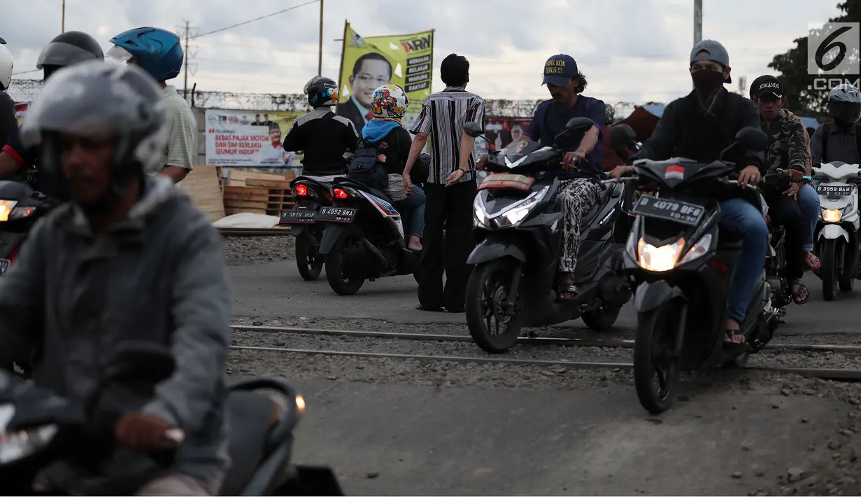 Pengendara motor melewati perlintasan kereta api tanpa palang pintu di kawasan Kelingkit, Rawa Buaya, Jakarta, Selasa (26/2). Warga setempat melakukan penjagaan swadaya agar perlintasan tanpa palang pintu tidak membahayakan. (Liputan6.com/Johan Tallo)