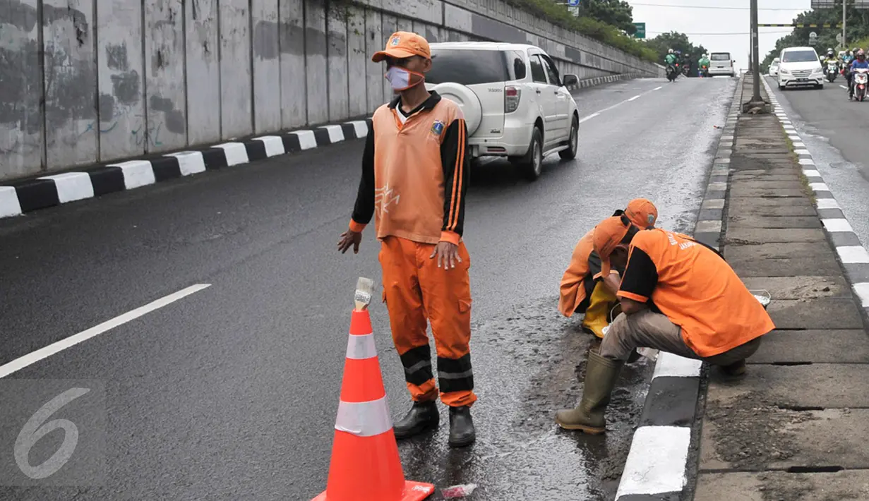 Sejumlah Petugas Pengelolaan Prasarana dan Sarana Umum (PPSU) mengecat pembatas jalan di Jalan Raya Pasar Minggu, Jakarta, Senin (27/2). Pengecatan dilakukan karena warna cat trotoar dan pembatas jalan sudah pudar. (Liputan6.com/Yoppy Renato)