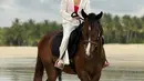 Kerennya Pevita Pearce naik kuda di pantai. Ia mengenakan swimsuit merah yang ditumpuknya dengan kemeja putih dan celana panjang putih yang serasi. [Foto: Instagram/pevpearce]