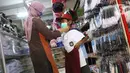 Pembeli mencoba seragam sekolah baru kepada anaknya di salah satu toko di Tangerang, Banten, Selasa (2/6/2020). Menjelang tahun ajaran baru, sejumlah pedagang di tempat tersebut mengeluh karena omzet penjualan seragam sekolah menurun drastis akibat pandemi COVID-19. (Liputan6.com/Angga Yuniar)