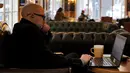 Seorang pria duduk dengan laptopnya di sebuah kafe di Beirut pada 14 Januari 2022. Kafe-kafe Beirut sekarang berfungsi sebagai tempat kerja pengganti bagi orang-orang yang bergulat dengan kekurangan listrik dan pemutusan internet yang berasal dari krisis ekonomi. (JOSEPH EID / AFP)