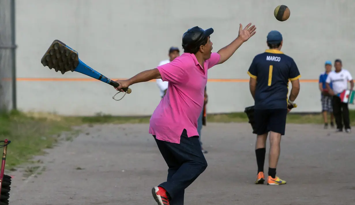 Seorang pria bersiap memukul bola saat bermain "pelota nacional" atau bola nasional di Quito, Ekuador (24/7). Olahraga ini banyak dimainkan di Narino, Kolombia, dan merupakan olahraga nasional Ekuador. (AFP Photo/Juan Cevallos)