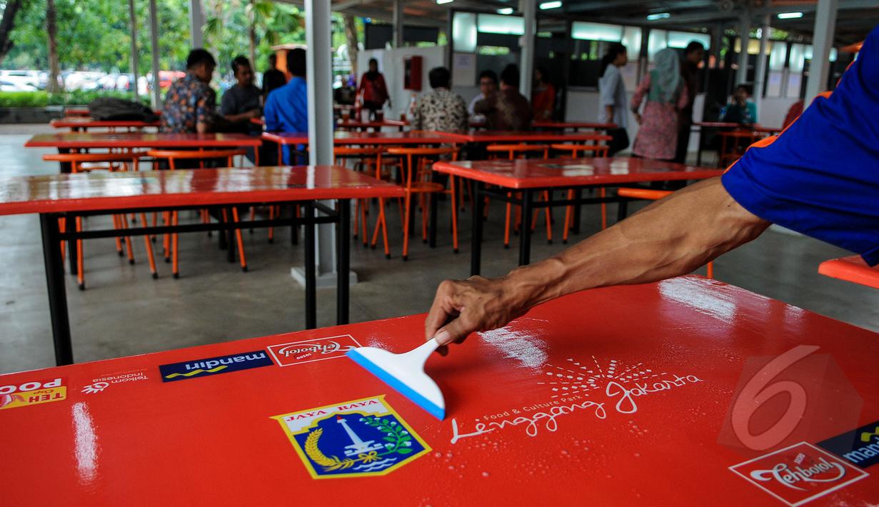 Seorang petugas tampak membersihkan meja kios 'Lenggang Jakarta', Jakarta, Jumat (17/4/2015). Kios 'Lenggang Jakarta' kini mulai ramai didatangi pengunjung. (Liputan6.com/Faizal Fanani)