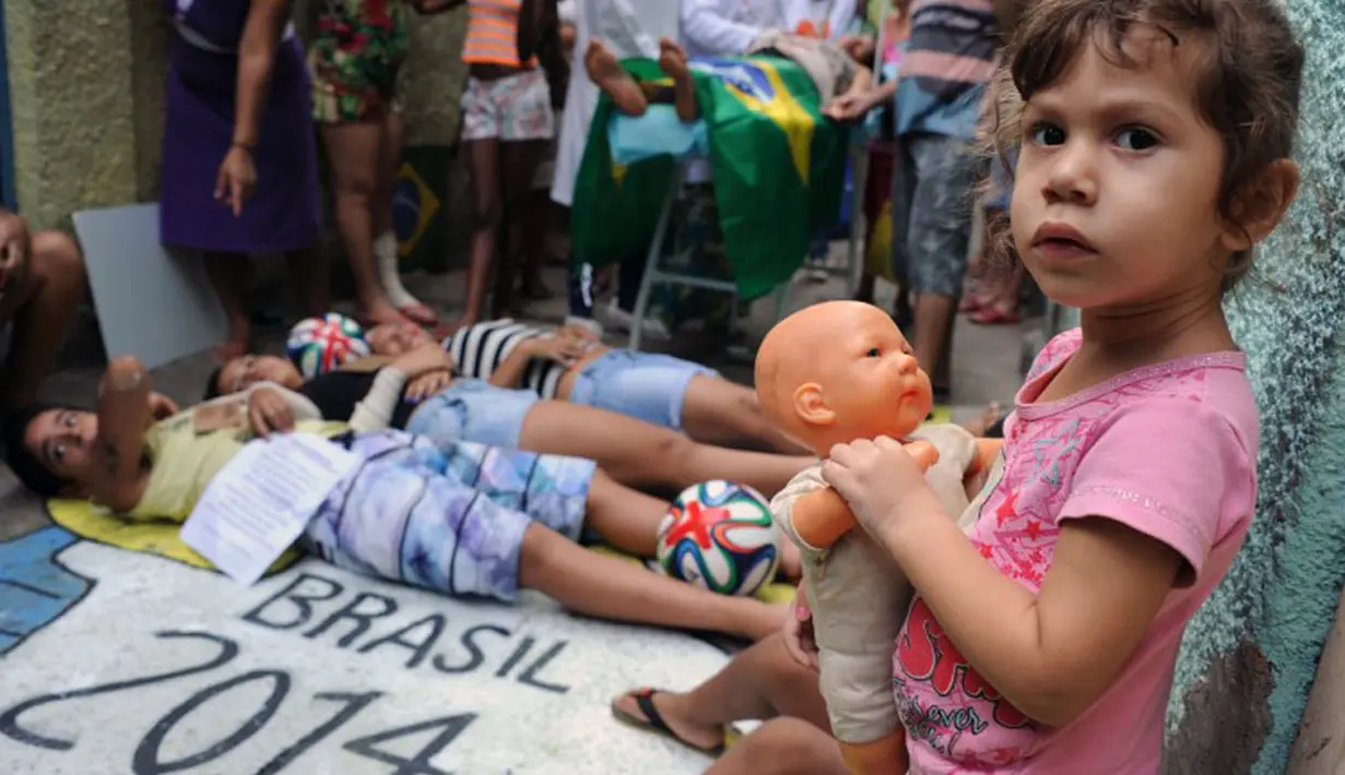 Seorang anak berpose berlatar belakang anggota LSM Rio de Paz yang sedang melakukan aksi protes terhadap sistem perawatan kesehatan masyarakat jelang pelaksanaan Piala Dunia 2014, Brasil, (10/5/2014). (AFP PHOTO/Tasso Marcelo) 