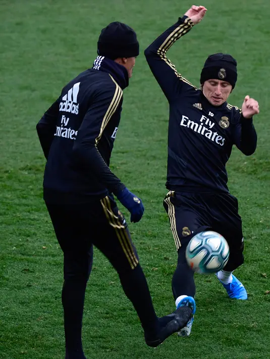 Gelandang Real Madrid, Luka Modric (kanan) berusaha merebut bola dari bek Eder Militao selama sesi latihan tim di fasilitas olahraga Real Madrid City di Madrid (17/12/2019). Real Madrid akan bertanding melawan Barcelona dalam laga El Clasico di Nou Camp. (AFP/Javier Soriano)