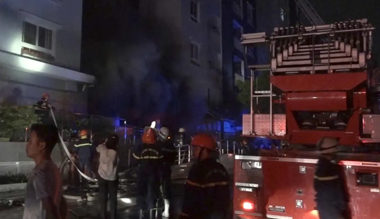 Petugas pemadam kebakaran berusaha memadamkan api untuk mencari orang yang terperangkap di kompleks kondominium selama kebakaran di Kota Ho Chi Minh, Vietnam, (23/3). (VnExpress via AP)