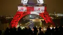 Wisatawan mengambil gambar Menara Eiffel pada Senin (16/11), yang dihiasi lampu berwarna bendera Prancis untuk menghormati para korban serangan teror di Paris hari Jumat (13/11) lalu. (REUTERS/Benoit Tessier)