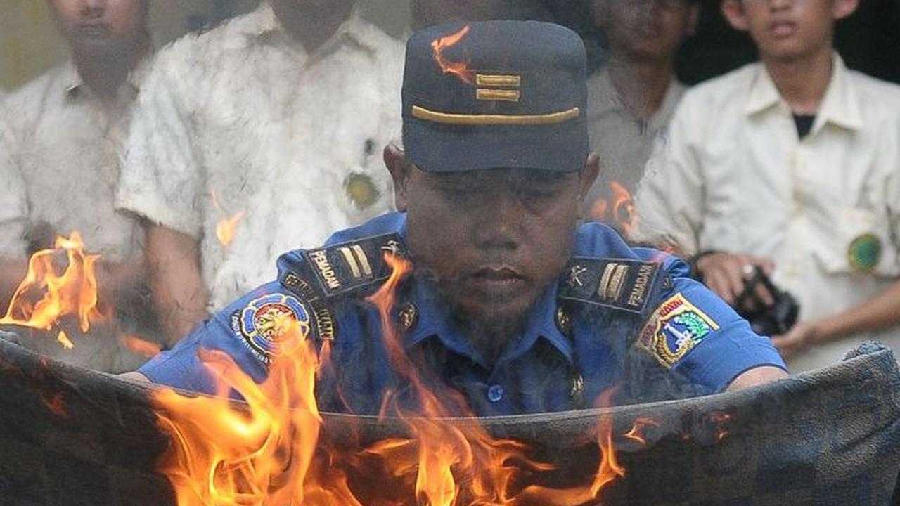Pemadam Kebakaran DKI Jakarta memperlihatkan salah satu cara memadamkan api menggunakan kain basah saat pelatihan.