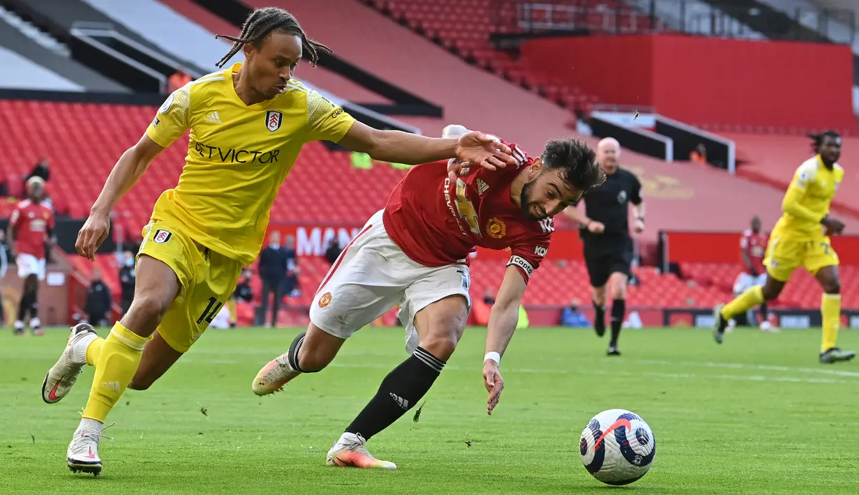 Striker Fulham, Bobby Decordova-Reid (kiri) berebut bola dnegan gelandang Manchester United (MU), Bruno Fernandes (tengah) pada pekan 37 Liga Inggris di Stadion Old Trafford, Rabu (19/5/2021) dinihari WIB. MU kembali gagal menang setelah ditahan imbang 1-1 oleh tamunya Fulham. (Paul ELLIS/POOL/AFP)