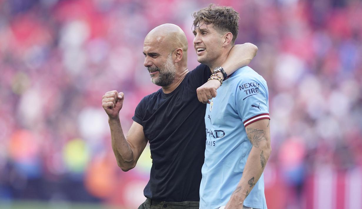 Ekspresi bahagia Pep Guardiola (kiri) dan John Stones setelah berhasil membawa Manchester City keluar sebagai juara Piala FA 2022/2023 dalam pertandingan final FA Cup melawan Manchester United yang berlangsung di Wembley, Sabtu (3/6/2023) WIB. (AP Photo/Dave Thompson)