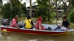 Penduduk setempat menggunakan perahu boat saat banjir melanda kawasan Jal Besar, Malaysia, Kamis (5/1). Banjir musiman di negara bagian pantai timur Malaysia memang kerap terjadi setiap tahun karena hujan muson. (AFP PHOTO / MOHD RASFAN)