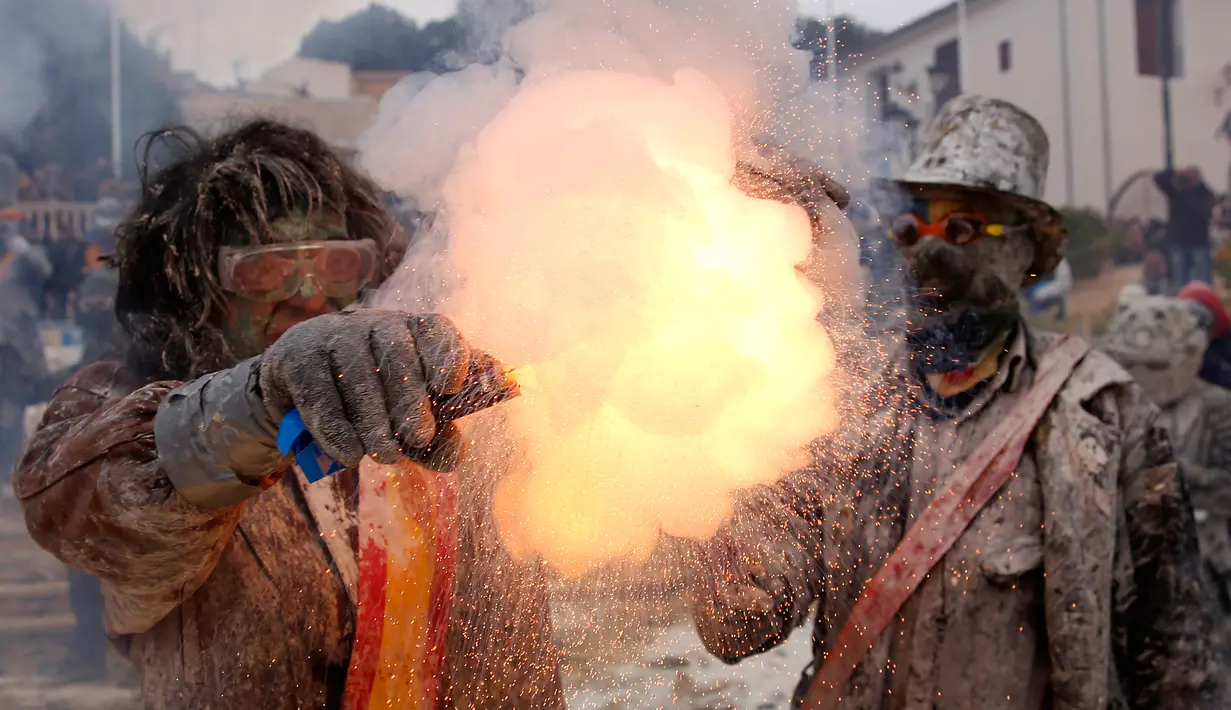 Peserta menyalakan petesan selama festival Els Enfarinats di kota Ibi dekat Alicante, Spanyol (28/12). Selama sekitar 200 tahun penduduk Ibi setiap tahun merayakan dengan pertempuran menggunakan tepung, telur, dan petasan. (AP Photo/Alberto Saiz)