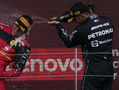 Pembalap Ferrari Carlos Sainz (kiri) melakukan selebrasi dengan pembalap Mercedes Lewis Hamilton di podium setelah memenangkan balapan F1 GP Inggris 2022 di Sirkuit Silverstone, Silverstone, Inggris, 3 Juli 2022. F1 GP Inggris 2022 dimenangkan oleh Carlos Sainz, selanjutnya diikuti Sergio Perez dan Lewis Hamilton. (AP Photo/Matt Dunham)