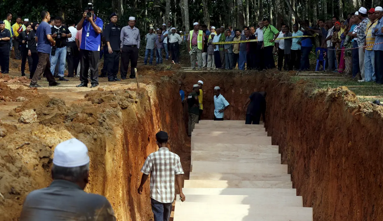 Sejumlah warga menyaksikan pemakaman massal jenazah yang di duga etnis Rohingya di Alor Setar, Malaysia, Senin (22/6/2015).  21 dari 106 jenazah tak dikenal yang ditemukan bulan lalu dimakamkan hari ini. (Reuters/Olivia Harris)