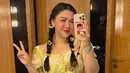 Sementara di hari kedua, Vicky tampil lebih playful dalam balutan ruffle blouse kuning cerah yang dipadukan dengan ripped jeans. Sling bag warna butter dan aksesori bunga matahari di rambut menambah sentuhan ceria pada look-nya. [@vickyshu].