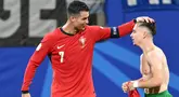 Penyerang Portugal #07 Cristiano Ronaldo mengucapkan selamat kepada #26 Francisco Conceicao setelah ia mencetak gol kedua timnya ke gawang Republik Ceko pada laga grup F Euro 2024 di Red Bull Arena, Leipzig, Rabu (19/6/2024) dini hari WIB. (Christophe SIMON / AFP)