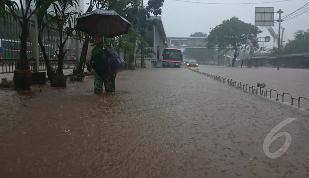 Seorang Pejalan kaki sedang berjalan melawati banjir yang berada di jalan Letjen Suprapto Cempaka Putih, Jakarta, Senin (9/2/2015). (Liputan6.com/Herman Zakharia)