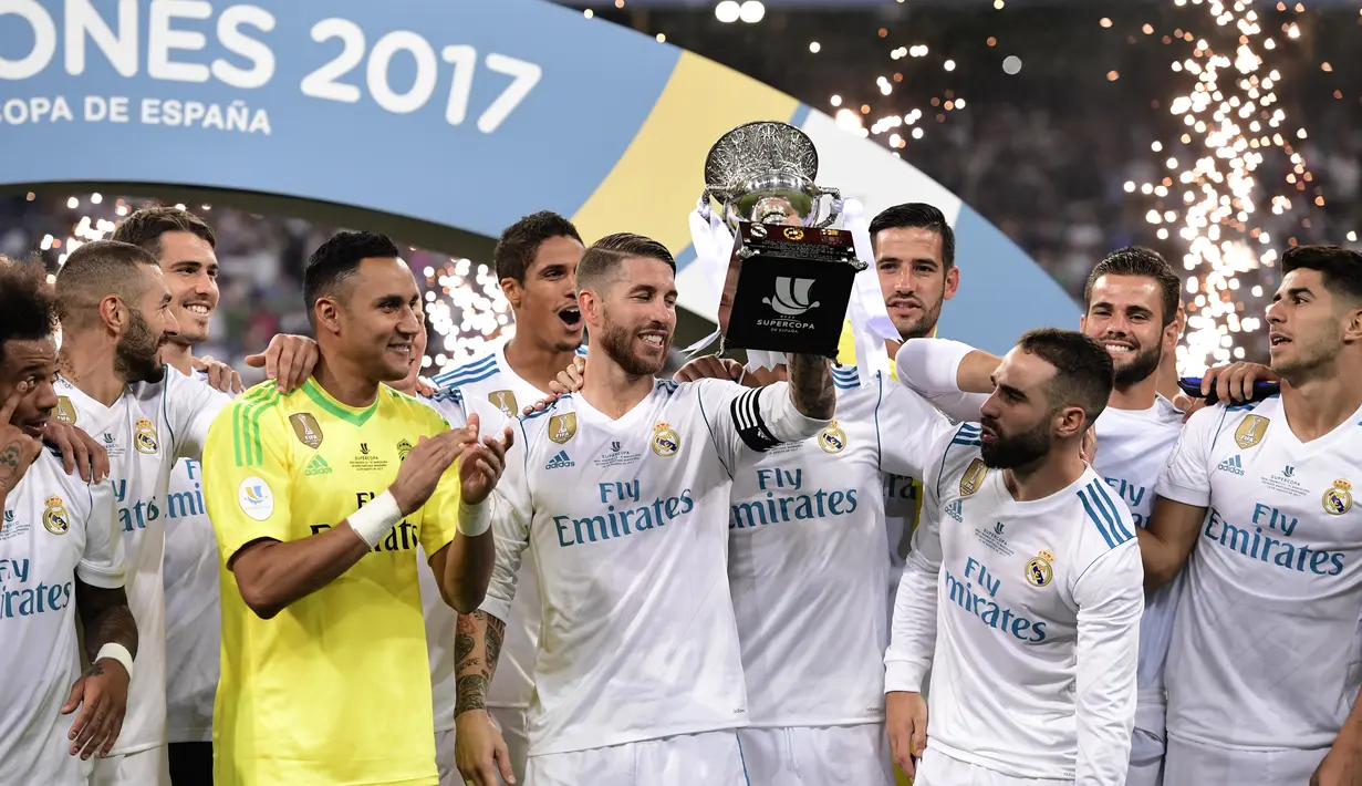 Sergio Ramos (tengah) mengangkat trofi Piala Super Spanyol 2017 usai mengalahkan Barcelona  pada leg kedua Piala Super Spanyol di Santiago Bernabeu stadium (16/8/2017). Real menang 2-0. (AFP/Javier Soariano)