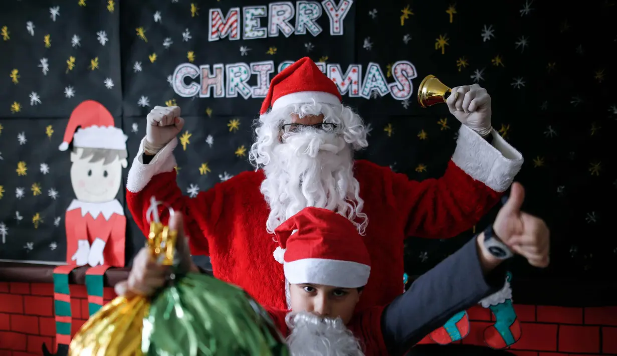 Seorang anak laki-laki Palestina sambil membawa kado foto bersama dengan santa claus  saat perayaan menyambut Hari Natal di Sekolah Amerika di Kota Gaza (20/12).  (AFP Photo/Mohammed Abed)