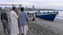 Penduduk setempat memeriksa kapal yang membawa ratusan etnis Rohingya yang mendarat di pantai di Lhokseumawe, provinsi Aceh, Senin (7/9/2020). Hampir 300 Muslim Rohingya ditemukan di sebuah pantai di provinsi Aceh dan dievakuasi oleh militer, polisi dan Relawan. (AP Photo/Zik Maulana)