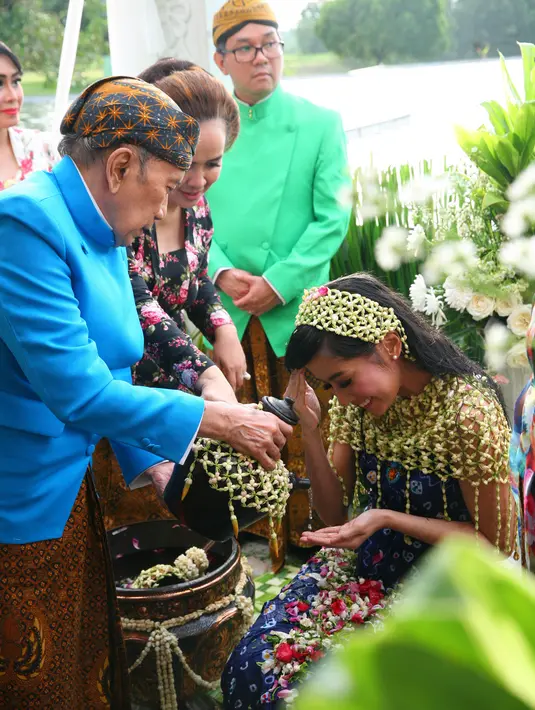 Rasti mengenakan kemben batik warna biru. Dipundaknya terlihat beberapa melati menutupi tubuhnya yang tidak kena kain. Air yang telah dicampur kembang di letakkan di sebelah kanannya. (Nurwahyunan/Bintang.com)