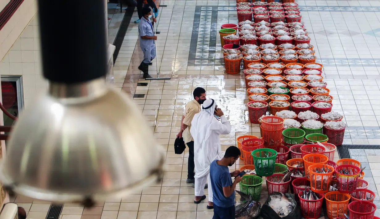 Orang-orang berbelanja selama pelelangan di pasar ikan di Kuwait City (8/8/2021). Pelelangan dibuka kembali di negara itu setelah enam bulan ditutup di tengah pandemi virus corona. (AFP/ Yasser Al-Zayyat)