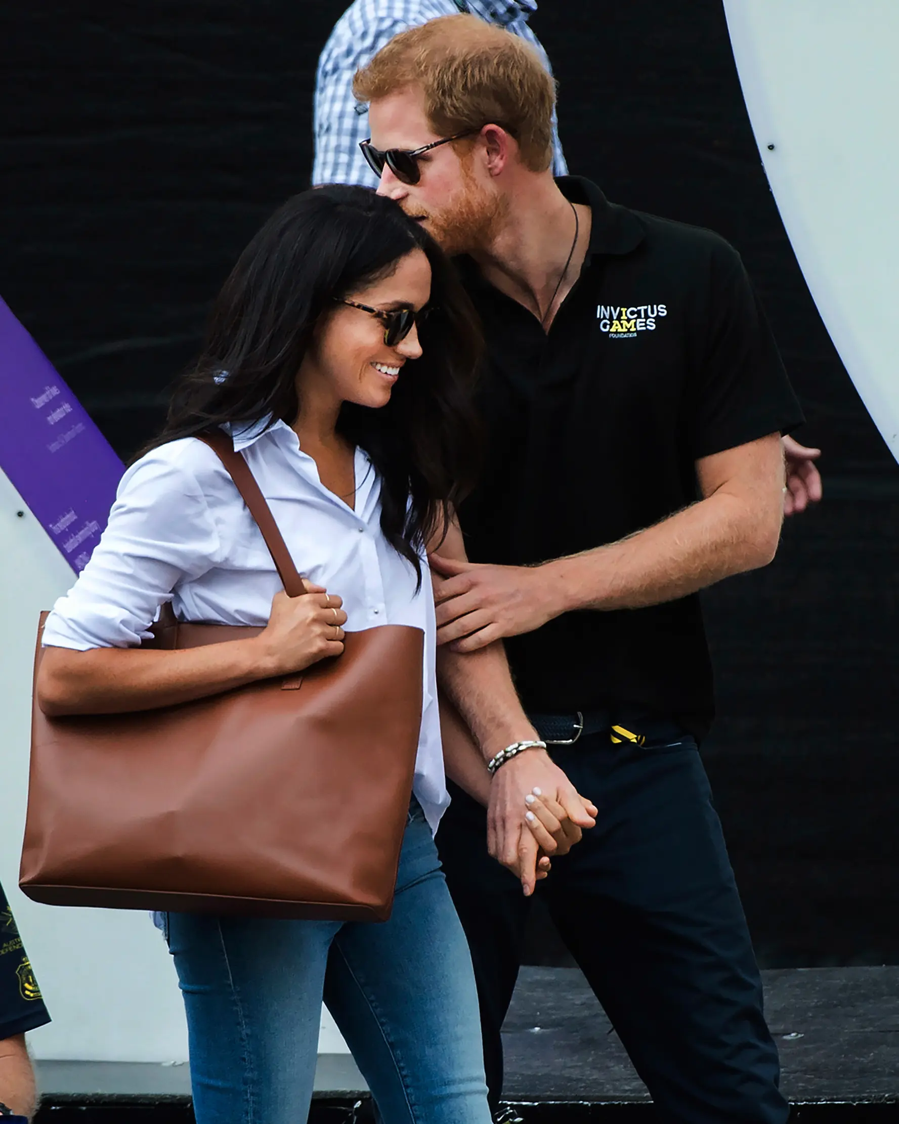 Pangeran Harry dan kekasihnya Meghan Markle bergandengan tangan saat menghadiri Invictus Games 2017 di Toronto, Kanada, Senin (25/9). Untuk kali pertama, keduanya menunjukkan kemesraan di depan publik. (Nathan Denette/The Canadian Press via AP)