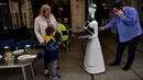 Santo Munoz (kanan) menyiapkan robot yang dikenal sebagai "Alexia" untuk melayani pengunjung sebuah bar di alun-alun Plaza del Castillo, di Pamplona, Spanyol pada 5 Juni 2020. Robot tersebut digunakan untuk mengurangi penyebaran virus corona Covid-19. (AP Photo/Alvaro Barrientos)