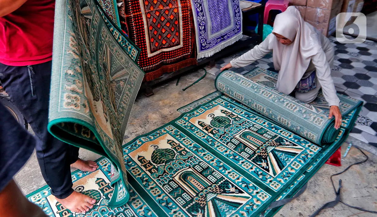 Pekerja menggulung karpet masjid pesanan pembeli di sebuah toko di kawasan Tanah Abang, Jakarta, Kamis (16/3/2023). (Liputan6.com/Angga Yuniar)