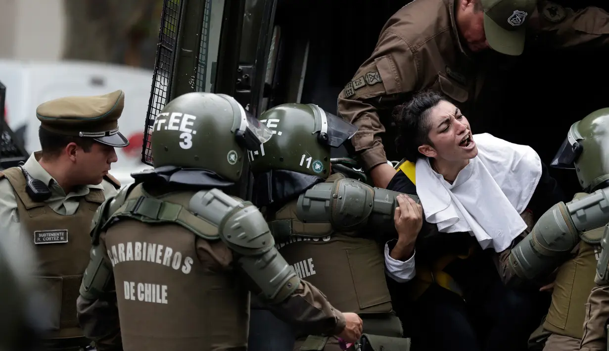 Seorang aktivis wanita mengenakan pakaian seperti biarawati diamankan polisi setempat setelah ia melakukan aksi protes dan memasang sepanduk pro-aborsi jelang kedatangan Paus Fransiskus di Chili (15/1). (AP Photo / Victor R. Caivano)