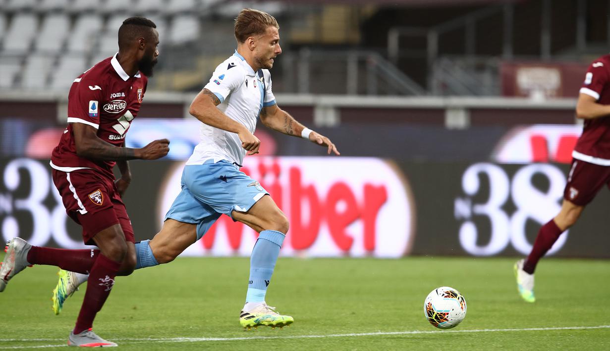 Gelandang Lazio, Ciro Immobile, berusaha melewati pemain Torino pada laga lanjutan Serie A pekan ke-29 di Stadion Olimpico Grande Torino, Rabu (1/7/2020) dini hari WIB. Lazio menang 2-1 atas Torino. (AFP/Isabella Bonotto)