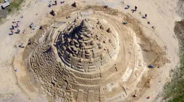 Pemahat beraktivitas di istana pasir tertinggi pada kompetisi tahunan "Sand Sculptures Festival" di Binz, Pulau Reugen di Laut Baltik, Jerman, 5 Juni 2019. Istana pasir karya seniman pasir bernama Thomas van Dungen itu didaulat sebagai istana pasir tertinggi yang pernah dibuat (Jens Büttner/dpa/AFP)