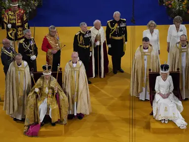 Raja Charles III mengenakan Mahkota St Edward dan Ratu Camilla mengenakan Mahkota Ratu Mary duduk selama upacara penobatan di Westminster Abbey, di London, Sabtu (6/5/2023). (Andrew Matthews/Pool via AP)