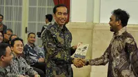 Glen Fredly memberikan DVD film Cahaya dari Timur kepada Presiden Jokowi saat peringatan Hari Film Nasional ke-65 di Istana Negara, Jakarta, Senin (30/3/2015). (Liputan6.com/Faizal Fanani)