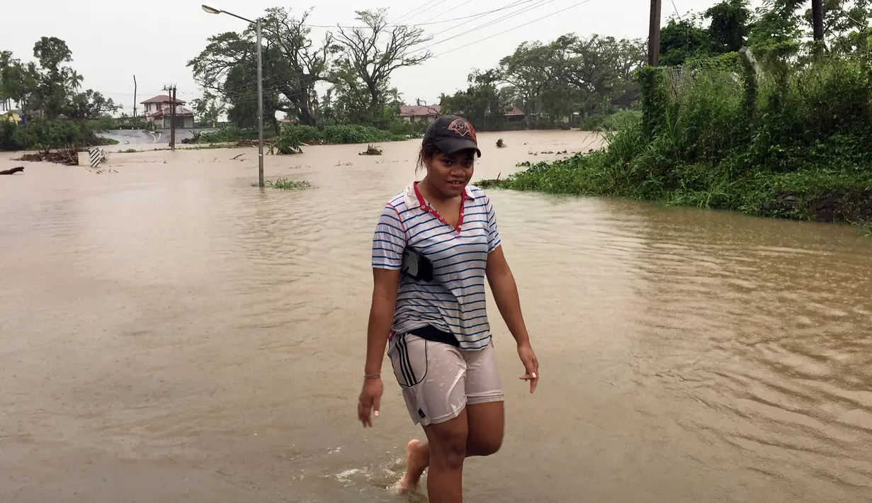 Seorang wanita berjalan melewati genangan banjir yang melanda Ba, wilayah barat Fiji, Rabu (6/4). Otoritas Fiji memerintahkan warganya untuk tetap berada di dalam ruangan seiring semakin mendekatnya siklon Tropis Zena. (NAZIAH ALI/MAI LIFE MAGAZINE /AFP)