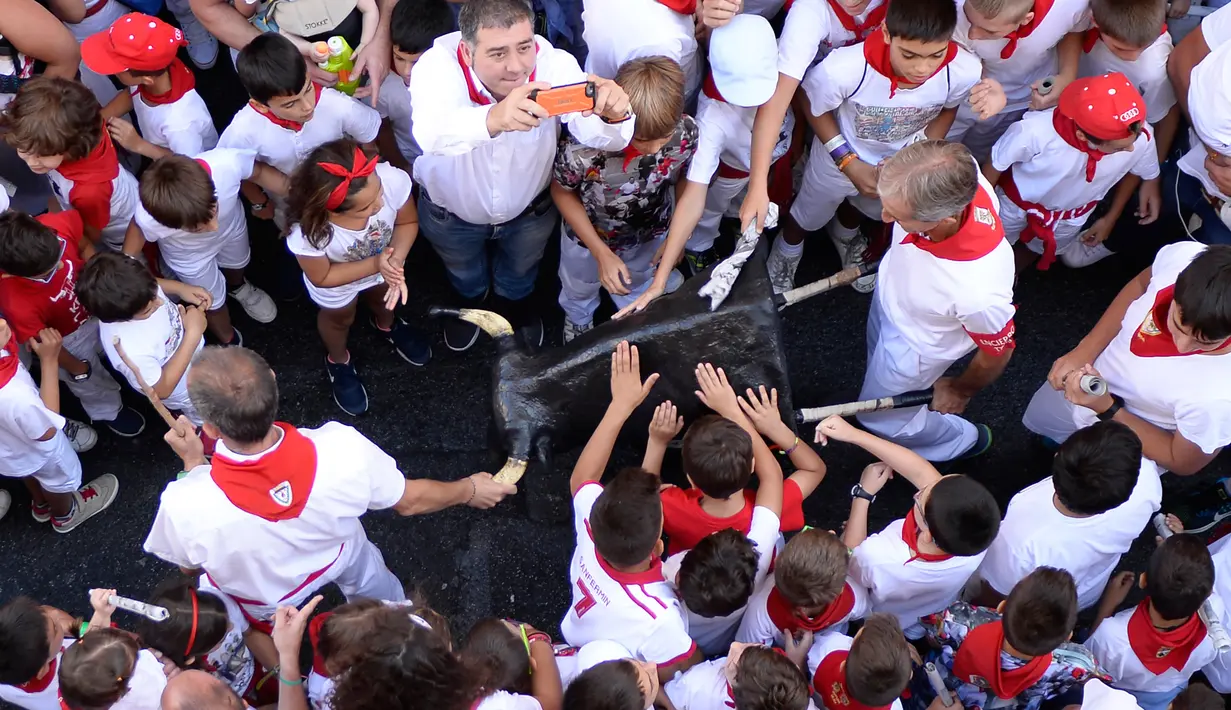 Anak-anak memegang banteng mainan saat Encierro Txiki selama Festival San Fermin di Pamplona, Spanyol (13/7). Encierro Txiki  atau Small Bull Run ini adalah bagian dari Festival San Fermin yang khusus untuk anak-anak. (AFP Photo/Ander Gillenea)