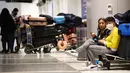 Pelancong menunggu dengan bagasi di terminal internasional Los Angeles di tengah lonjakan kasus varian omicron, Selasa (21/12/2021). AAA memperkirakan lebih dari 109 juta orang Amerika akan melakukan perjalanan selama musim liburan antara 23 Desember - 2 Januari. (MARIO TAMA/Getty Images via AFP)