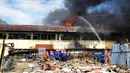 Petugas pemadam kebakaran berusaha memadamkan api yang membakar ruko di kompleks Kanjengan, Pasar Johar Semarang, Sabtu (18/6). Dugaan awal, kebakaran tersebut diakibatkan hubungan pendek arus listrik di salah satu toko di Blok E. (Liputan6.com/Gholib)