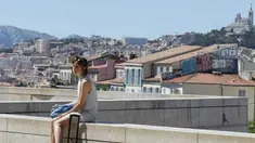 Seorang wanita duduk dengan latar belakang suasana kota di Marseille, Prancis, Minggu (3/7/2016). Marseille merupakan daerah pesisir di selatan Prancis dengan pesona keindahan alam. (Bola.com/Vitalis Yogi Trisna)