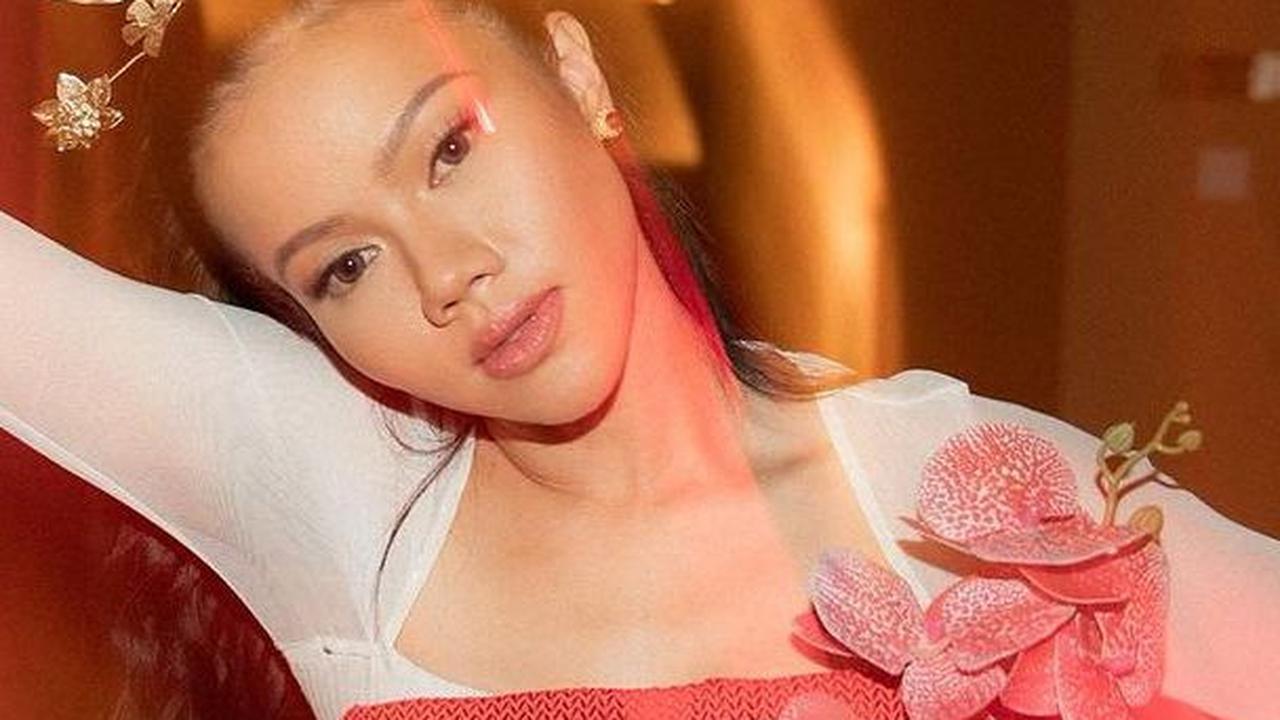 Guna mengusir kesan monoton di bajunya, Yura menambahkan sentuhan aksesoris bunga anggrek di bagian depan. Bunga tersebut memiliki tone warna gradasi pink percampuran dari merah dan putih.