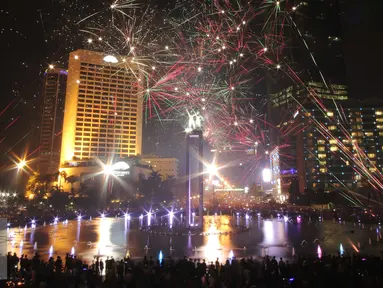 Warga saat menikmati malam tahun baru dengan dengan pertunjukan kembang api di Bundaran HI, Jakarta, Jumat (1/1/2016) malam. Kemeriahan kembang api tersebut merupakan bentuk perayaan pergantian tahun 2015 menuju 2016. (Liputan6.com/Angga Yuniar)