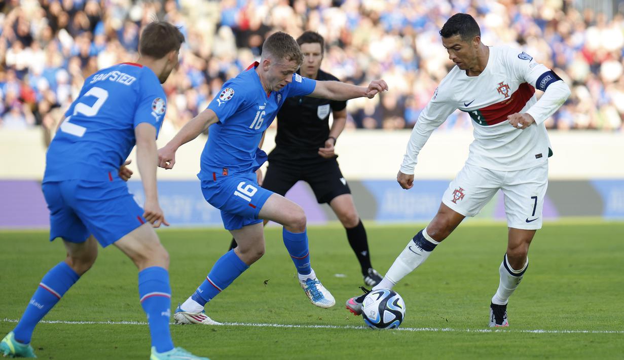 Pemain Timnas Portugal, Cristiano Ronaldo (kiri), berusaha melwati hadangan dua pemain Islandia dalam pertandingan lanjutan grup J Kualifikasi Euro 2024 yang berlangsung di Laugardalsvollur, Reykjavik, Rabu (21/6/2023) dini hari WIB. Pertandingan ini merupakan penampilan CR7 yang ke-200 bersama Portugal. (AP Photo/Arni Torfason)