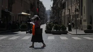 Seorang wanita melambaikan kipasnya saat berjalan di pusat kota Roma, Selasa, 22 Agustus 2023. (AP Photo/Gregorio Borgia)