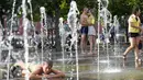 Sepasang kekasih berbagi momen saat anak-anak bermain di air mancur sebuah taman di sebelah tanggul Sungai Moskow, di Moskow, Rusia, Rabu (14/7/2021). Cuaca panas di Moskow berlanjut dengan suhu mencapai 34 derajat Celcius (93,2 Fahrenheit) dalam sehari. (AP Photo/Pavel Golovkin)