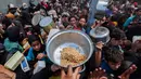 Warga Palestina berkumpul untuk menerima makanan hangat di titik distribusi makanan di kamp Nuseirat, Jalur Gaza Tengah pada 21 Mei 2025. (Eyad BABA/AFP)