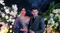 Pasangan aktris Bollywood Priyanka Chopra dan musisi Nick Jonas berpose untuk resepsi kedua pernikahan mereka di Mumbai, India, Rabu (19/12). Nick Jonas tampil klasik dan chic mengenakan setelan biru tua dan kemeja hitam. (AP/Rajanish Kakade)