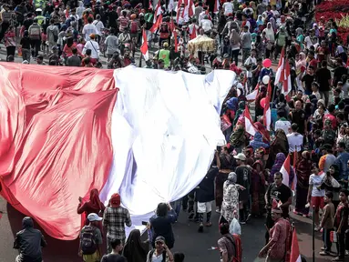 Peserta membentangkan bendera merah putih raksasa pada Karnaval Cinta Budaya NKRI di MH Thamrin, Jakarta, Minggu (20/11). Ribuan peserta yang terdiri dari berbagai elemen membawa dan mengibarkan bendera merah putih. (Liputan6.com/Faizal Fanani)