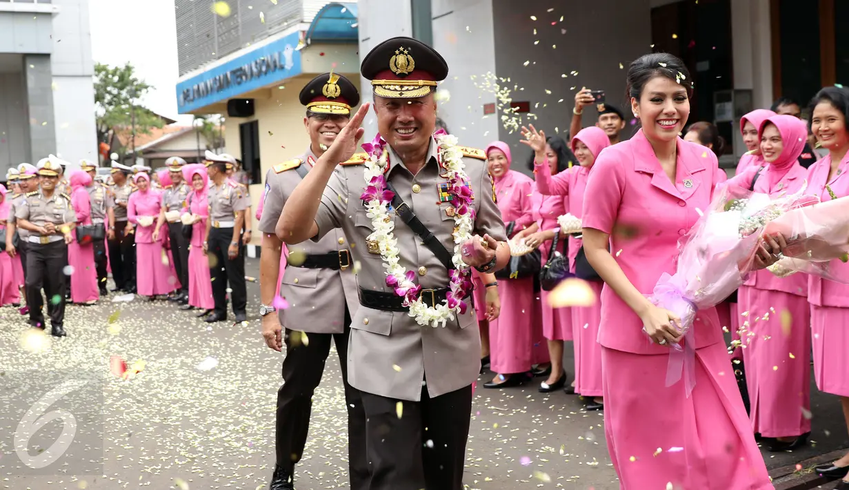 Irjen Pol Agung Budi M (tengah) bersama istri melewati taburan bunga usai upacara pelepasan jabatan Kakorlantas Polri di Jakarta, Rabu (4/1). Selanjutnya, Irjen Pol Agung Budi M menjabat Kapolda Sumsel. (Liputan6.com/Helmi Fithriansyah)