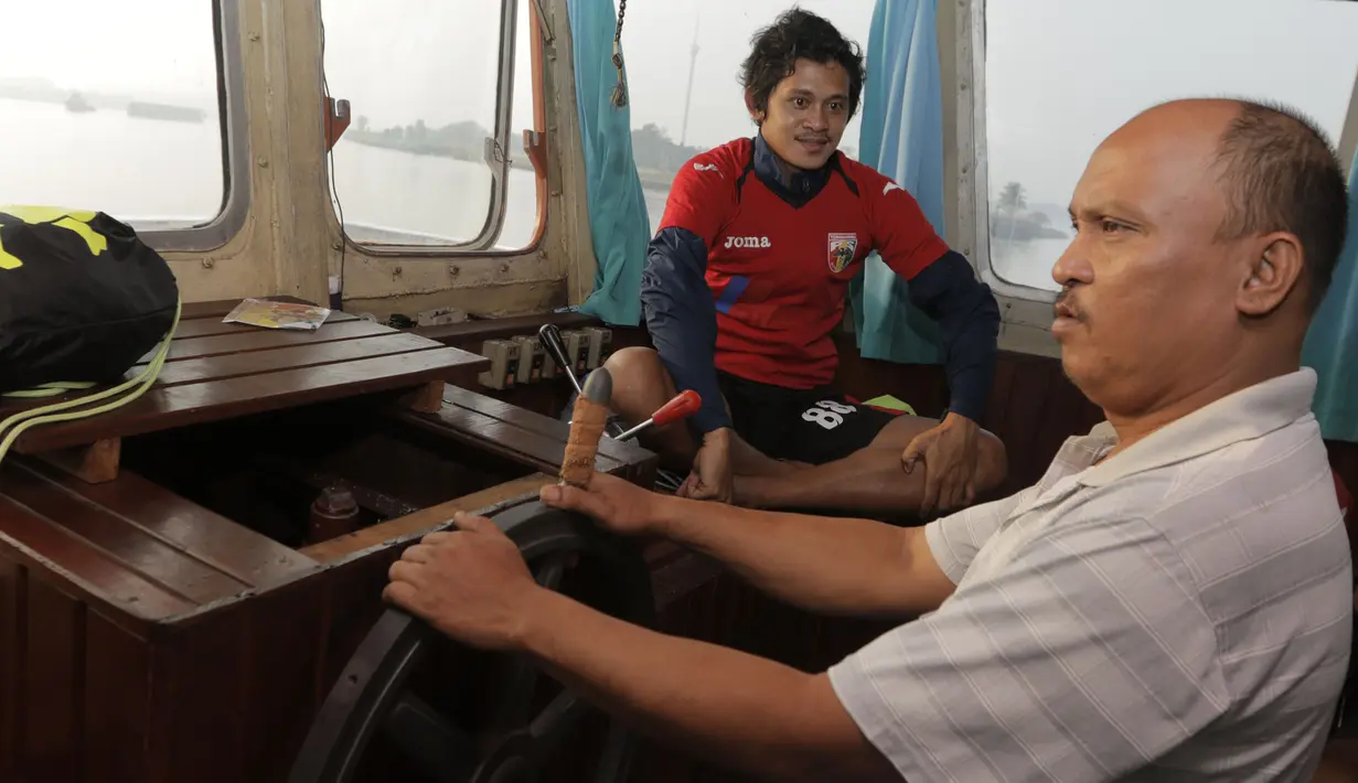 Pemain Mitra Kukar, Rizky Pellu duduk dekat nahkoda kapal feri saat berangkat latihan menyeberangi Sungai Mahakam menuju Stadion Aji Imbut, Tenggarong, Kaltim, Sabtu (3/10/2015). (Bola.com/Vitalis Yogi Trisna)