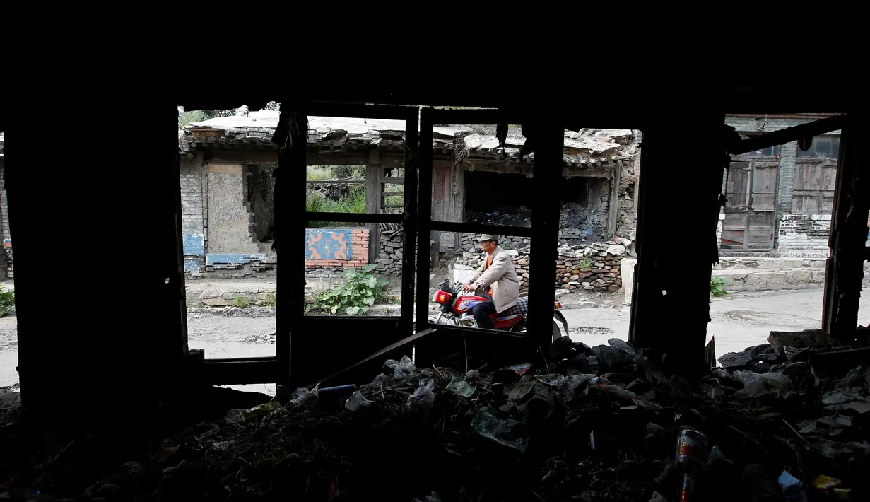 Warga melintas di rumah-rumah yang ditinggal penduduknya di Kouquan kotapraja Datong, Provinsi Shanxi, Tiongkok, (1/8). (REUTERS/Jason Lee)